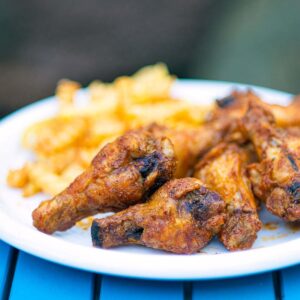 Air Fryer Chicken Wings seasoned in Nashville hot seasoning served with with fries on a white plate.