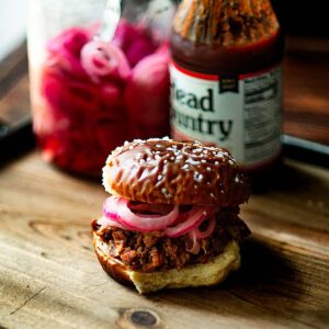 Pulled Pork Sandwich Served with Pickled onions on a salted pretzel bun.