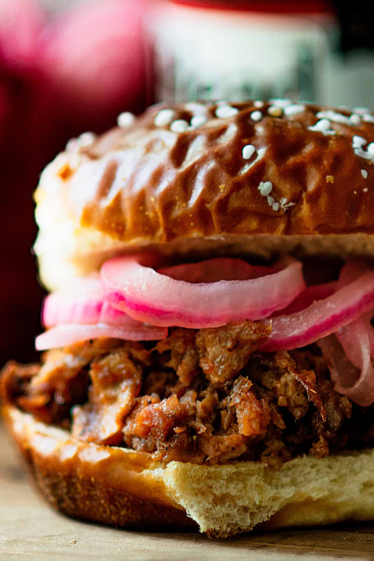 Pulled pork sandwich served with pickled onions and a salted pretzel bun.