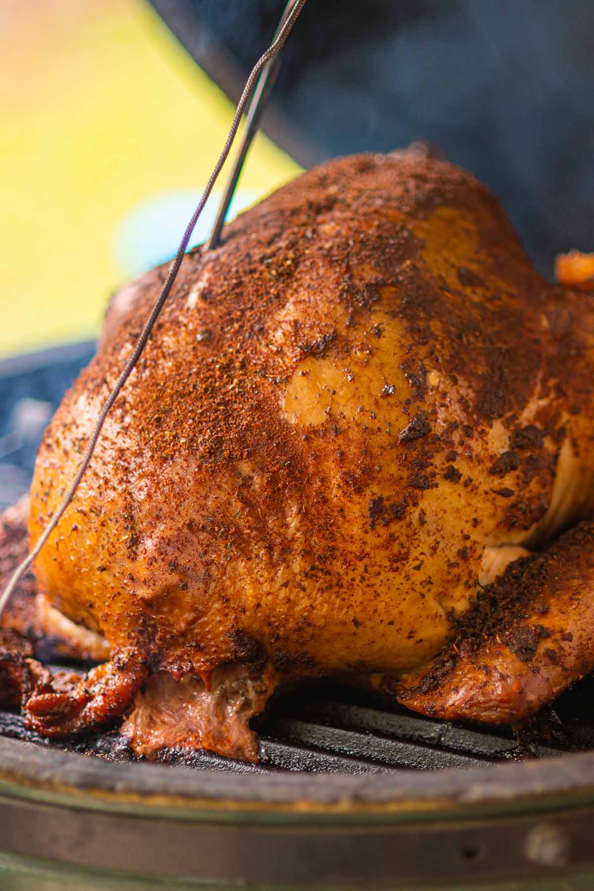 A whole turkey being smoked on a big green egg seasoned with cajun seasoning.