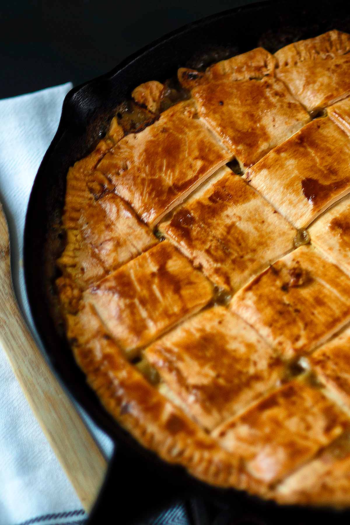 Cajun smoked turkey pot pie baked in a cast iron skillet with a woven pie crust.