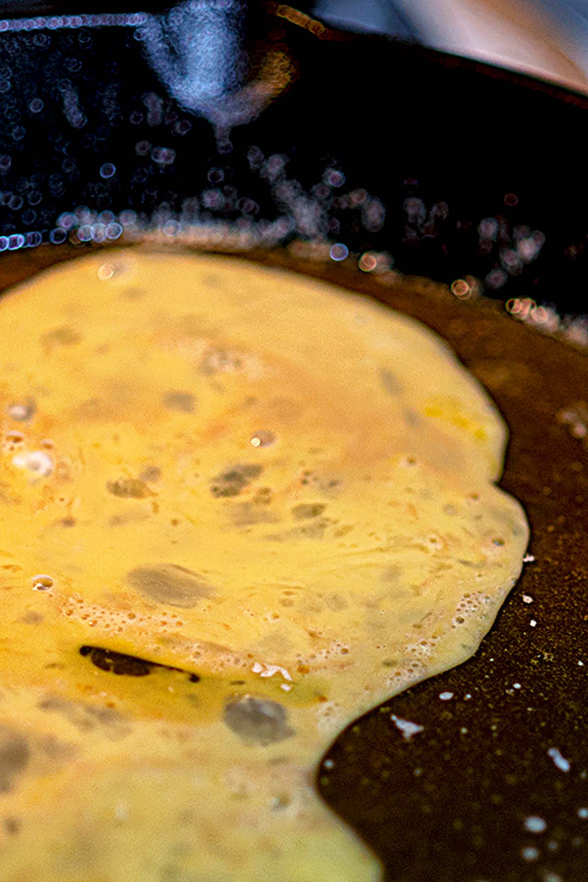 Egg being added to the cookie dough base in a cast iron skillet.