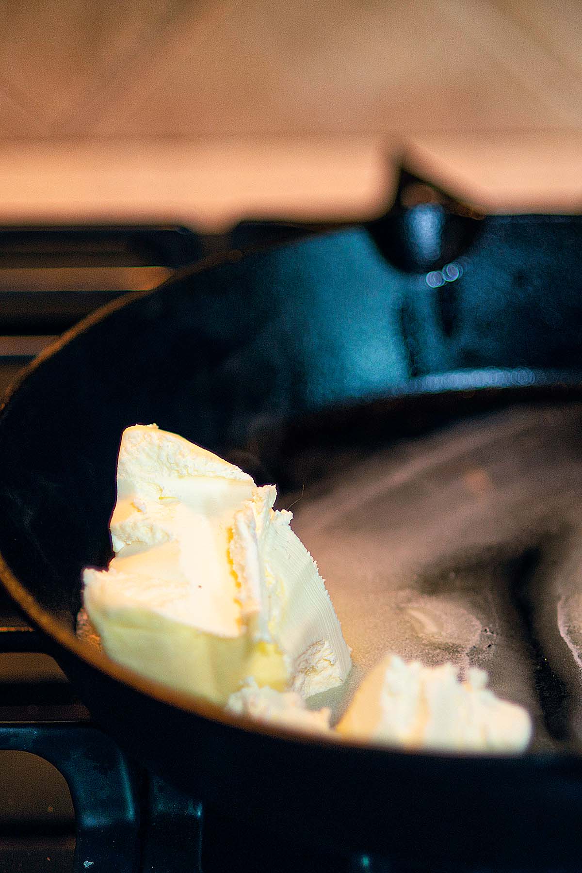A butter block being melted in a cast iron skillet.