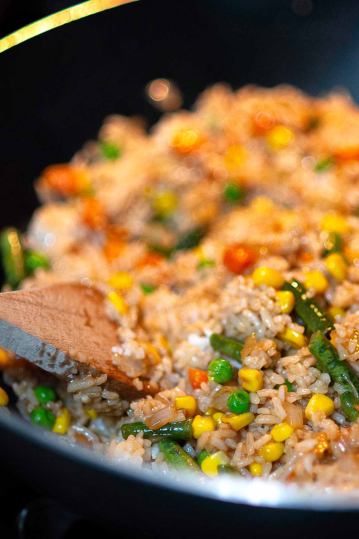 Fried rice in a wok with a wooden spatula.