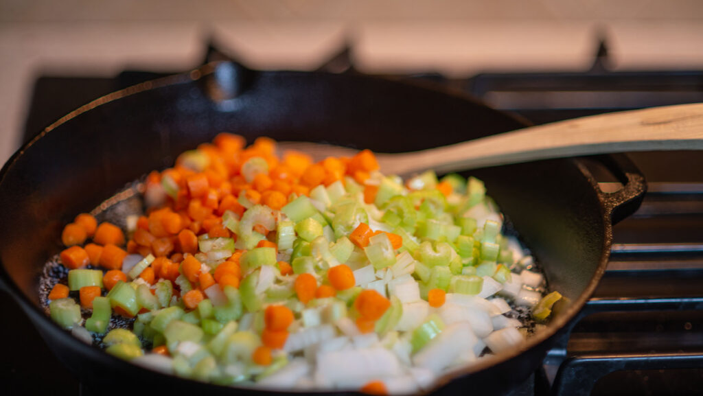 Mirepoix added to butter in a cast iron skillet for smoked turkey pot pie.