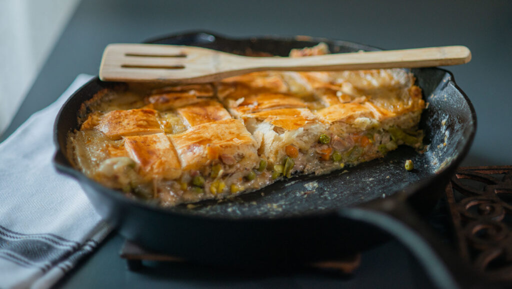Smoked Turkey Pot Pie Served in a cast Iron Skillet with a wooden spatula.