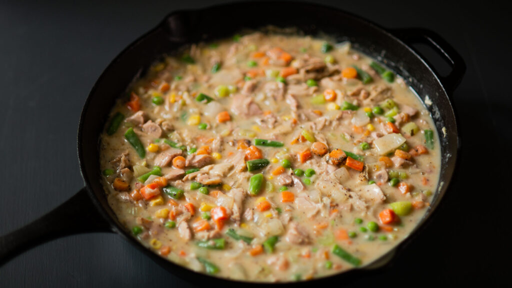 All ingredients for Smoked Turkey Pot Pie filling combined in a cast iron skillet.