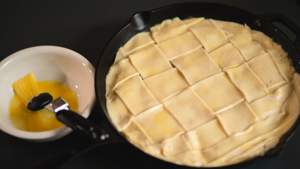 Woven Pie Crust on top of Smoked Turkey Pot Pie in a cast iron skillet.