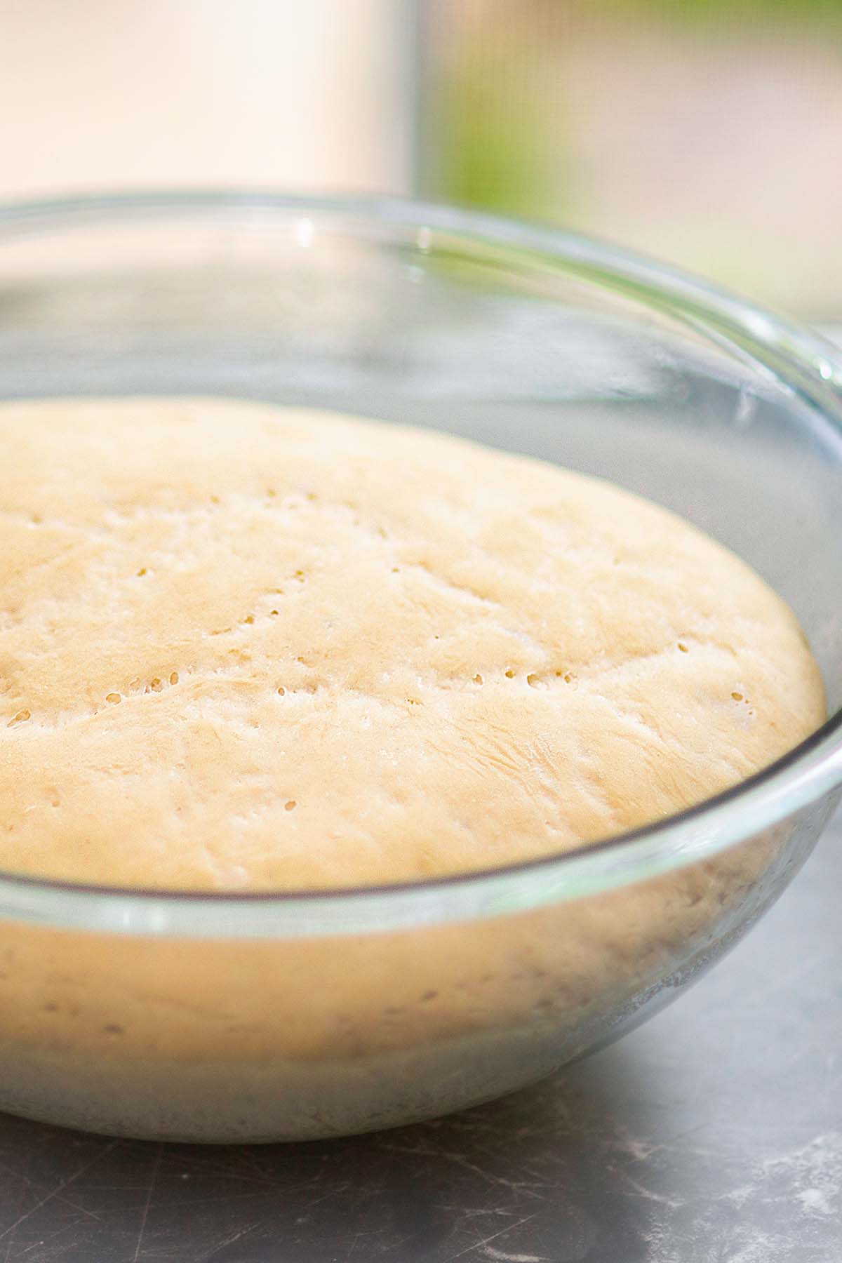 White bread dough rising in a glass bowl.
