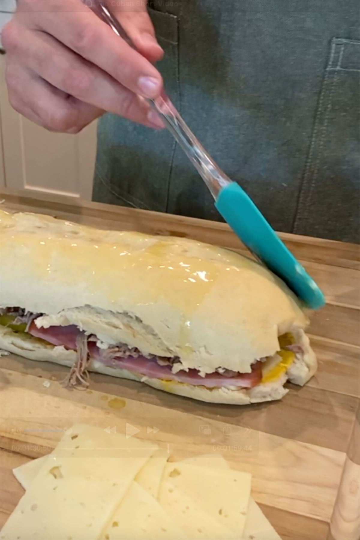 Butter being brushed onto the outside of a cuban sandwich.