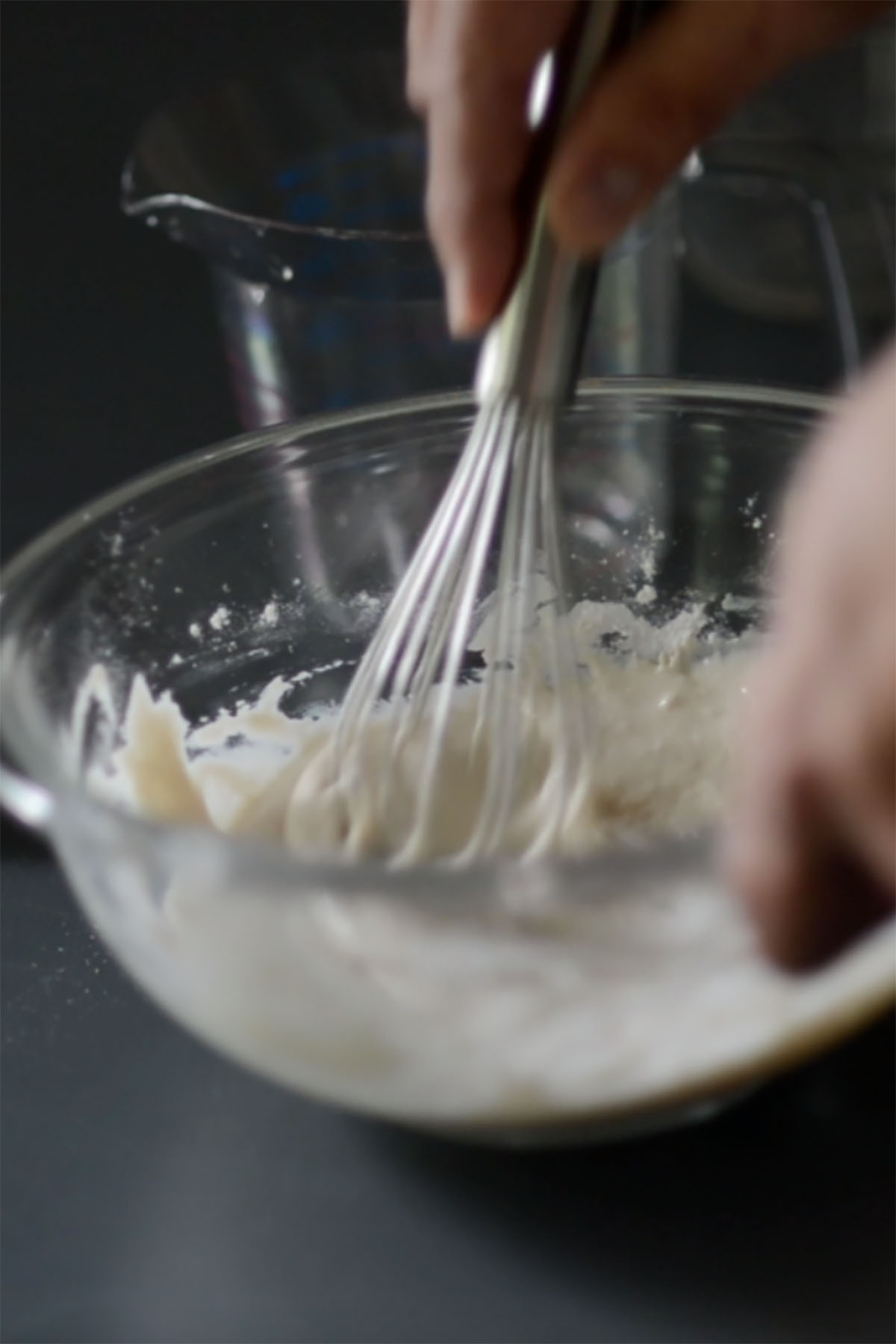 Bread starter being whisked in a glass mixing bowl.