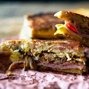 Cuban Sandwich on butcher paper sliced and served with pickles.