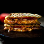 Grilled Pimento Cheese Sandwich Sliced in half with bacon and sliced tomato.