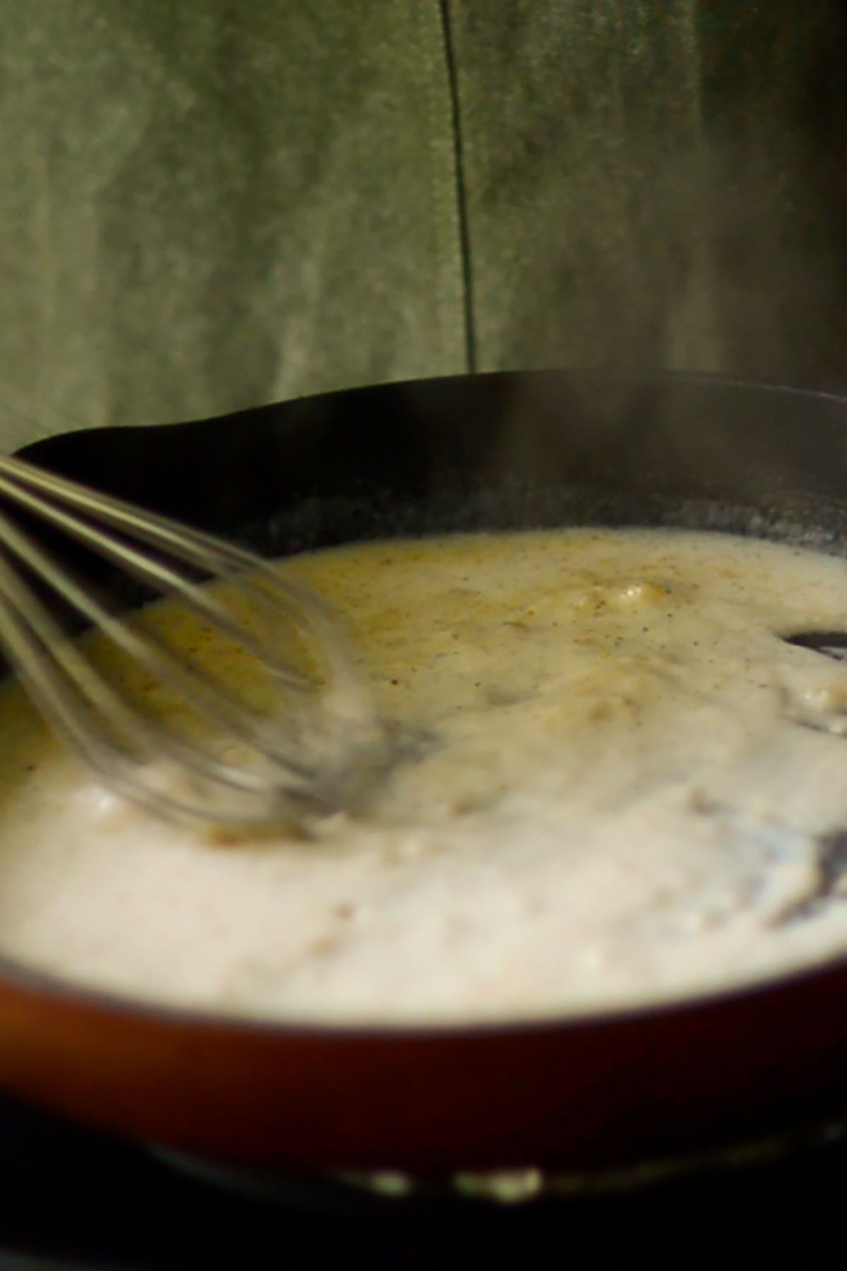 Mornay sauce base being whisked in a small cast iron skillet.