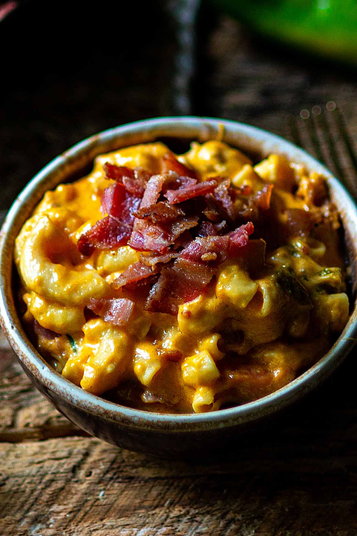 Hatch Green Chile Mac and Cheese served in a brown rustic bowl and topped with fresh bacon bits.