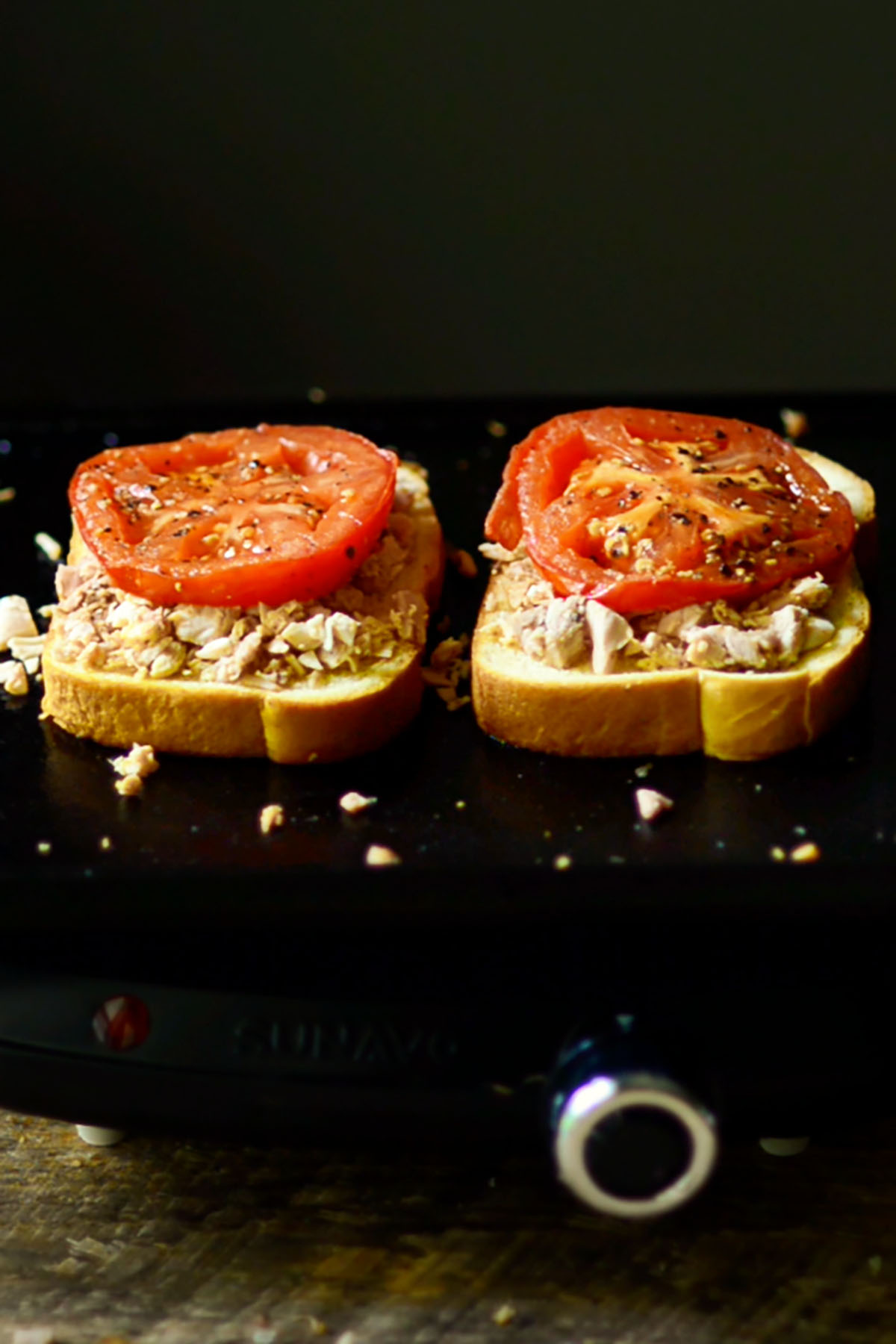 Sliced Texas toast on a cast iron griddle topped with chopped turkey and a slice of tomato.