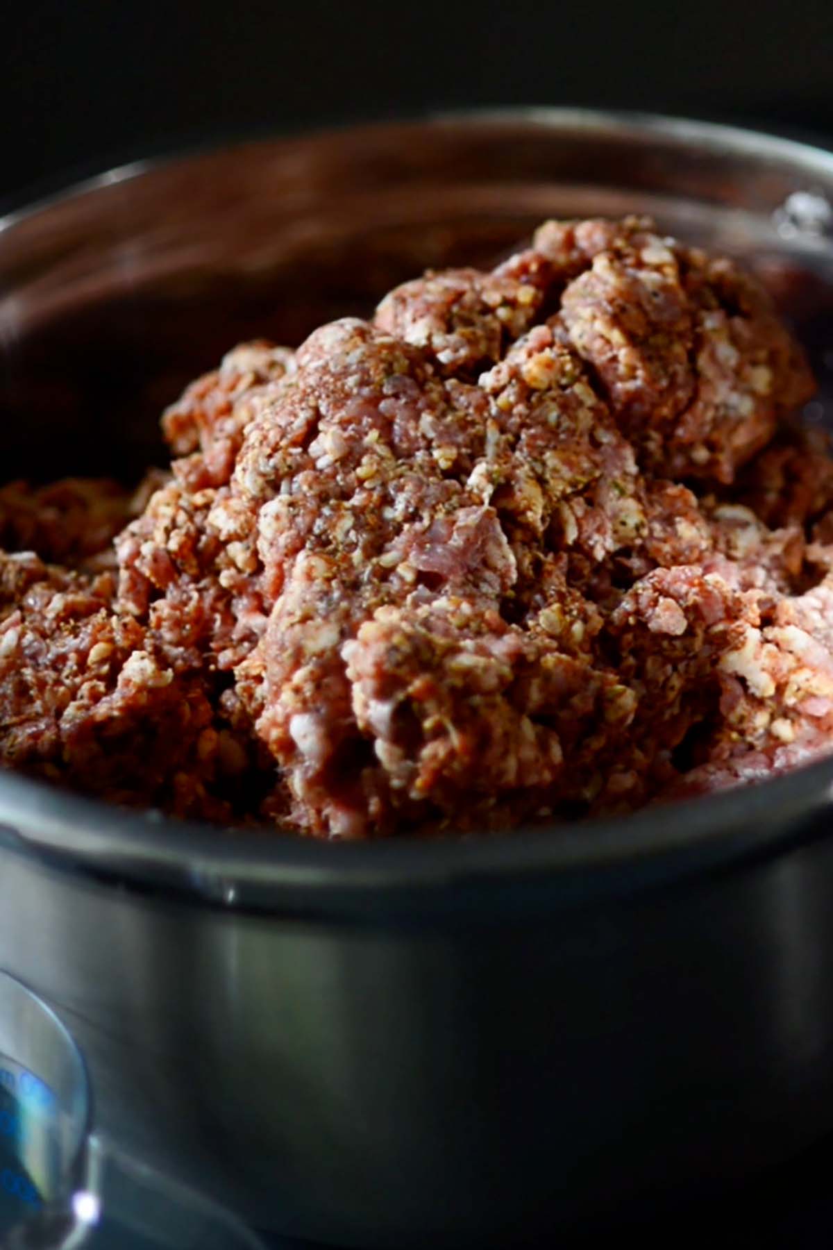Ground veal and seasonings mixed thoroughly into ground pork shoulder in a mixing bowl.