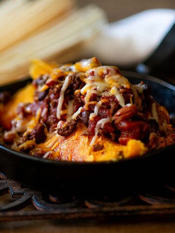 Mississippi Delta Hot Tamales Served in a cast iron skillet topped with chili and cheese.