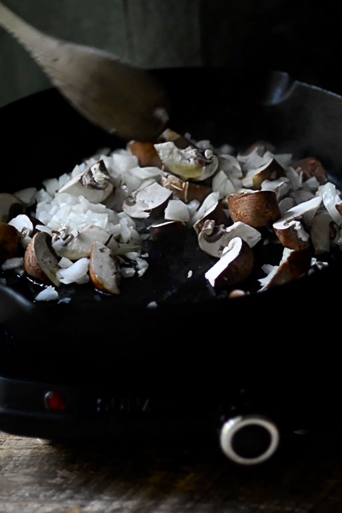 Diced onions and mushrooms sautéing in a cast iron skillet.