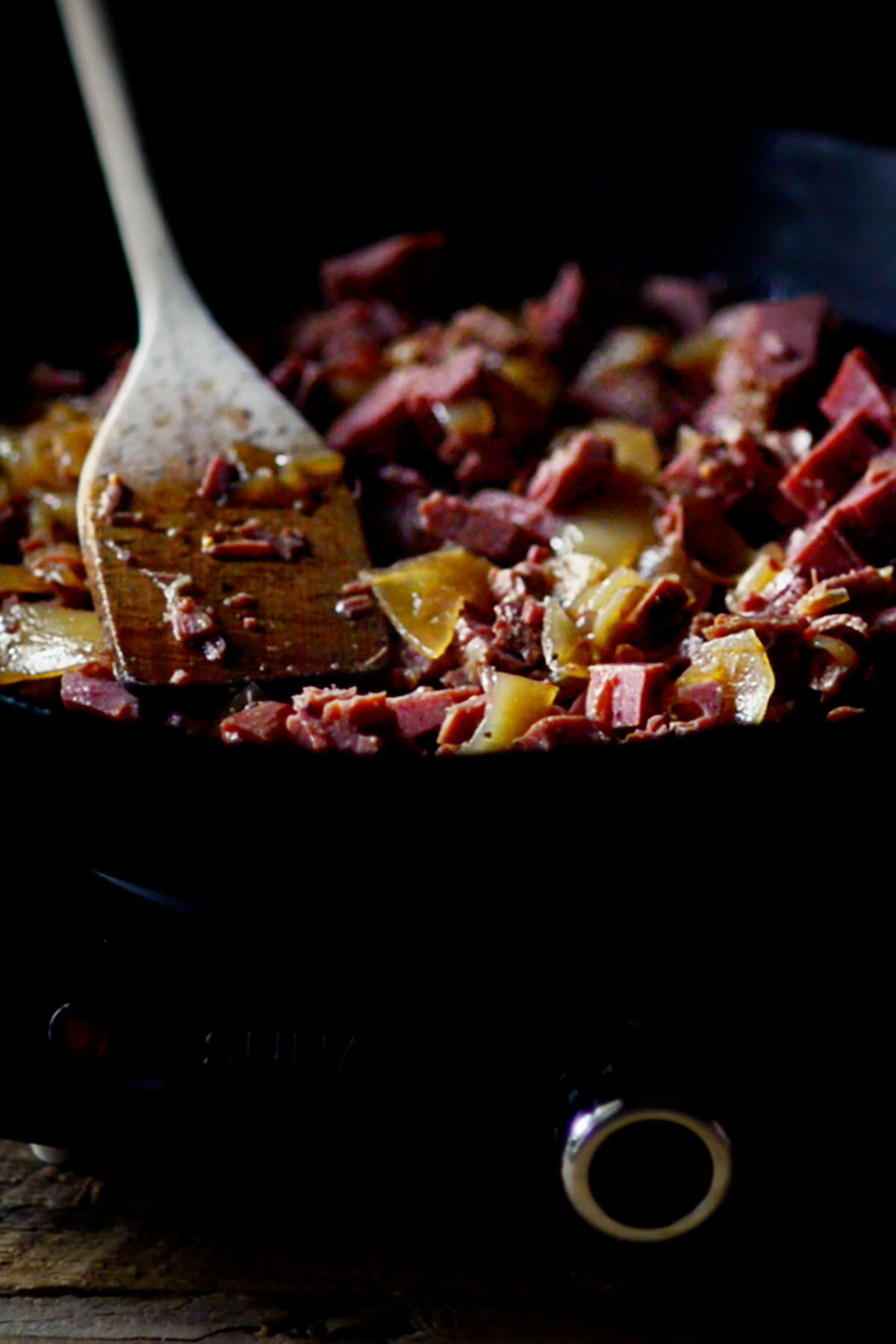 Cooked corned beef brisket and onions searing in a cast iron skillet.