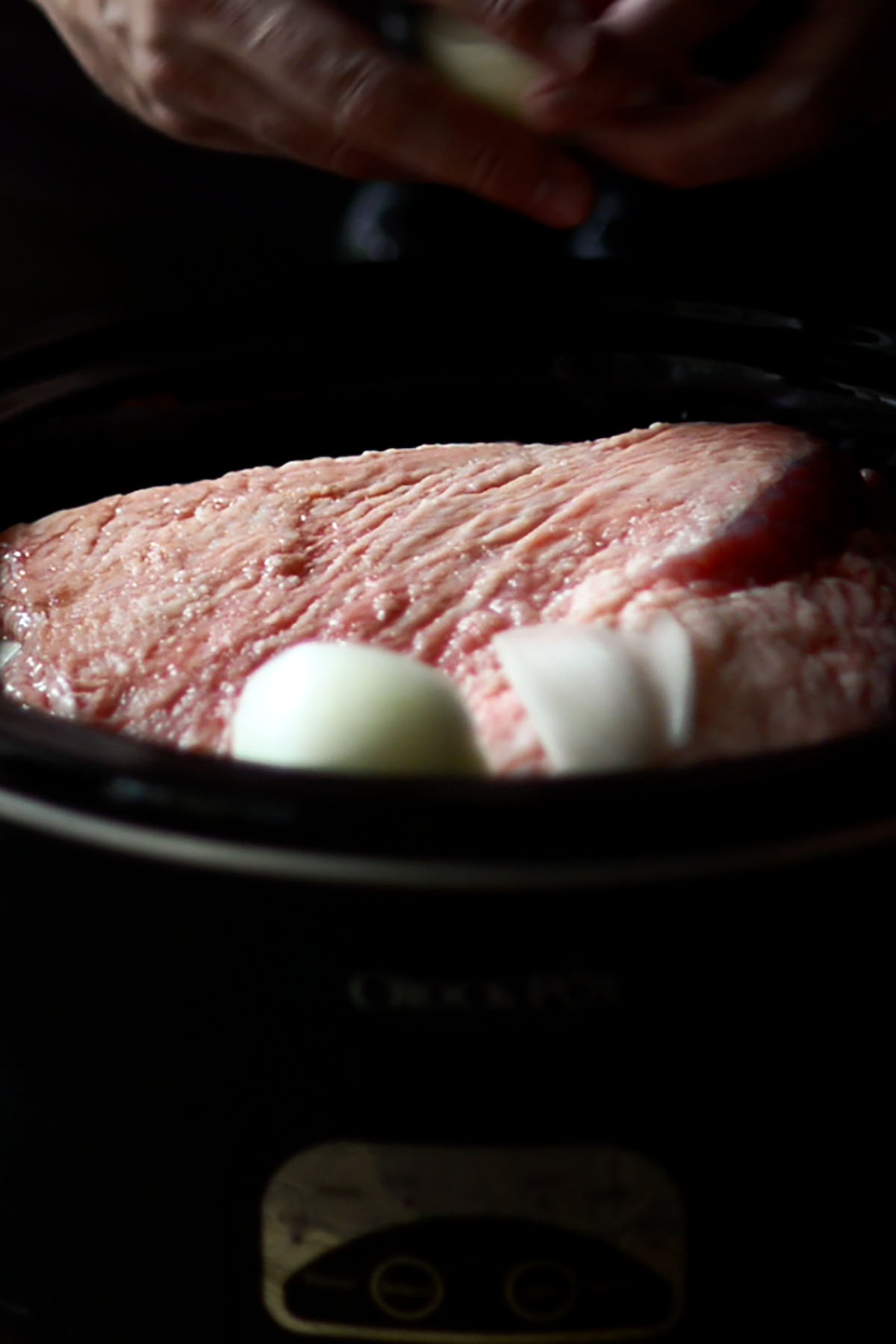 Corned beef brisket with quartered onions in a Crock Pot.