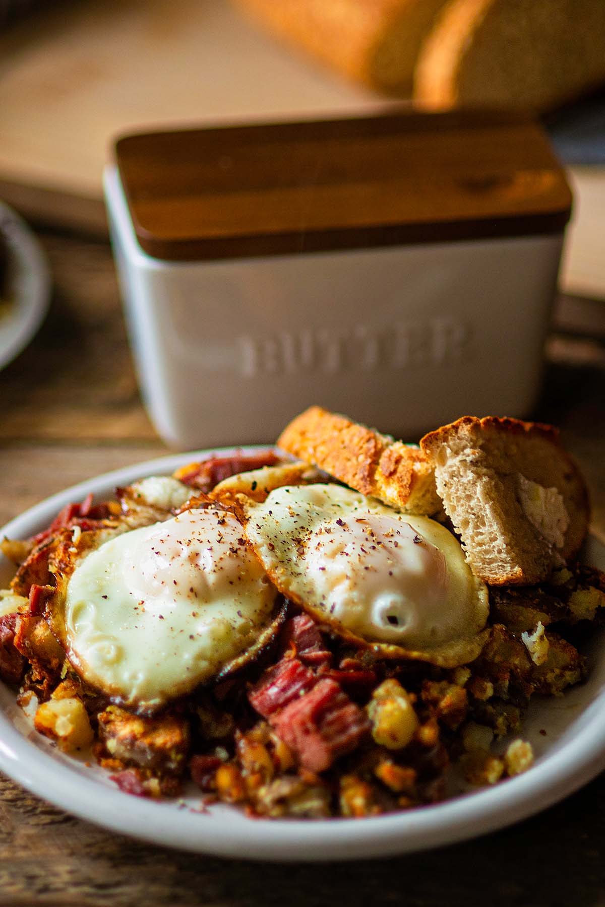 Corned beef hash topped with two fried eggs and served with buttered toast.