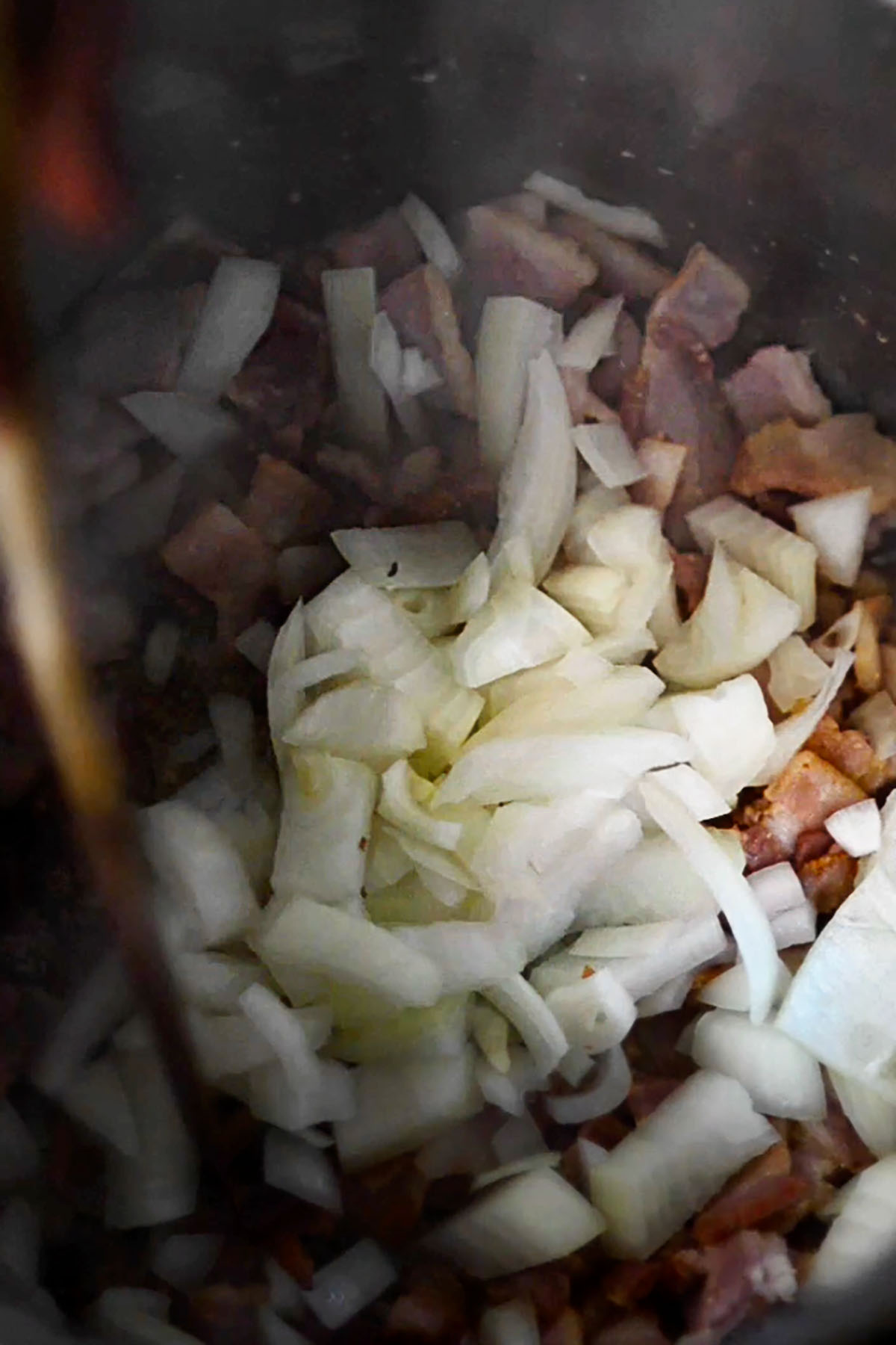 Diced onions and bacon cooking in an Instant Pot.