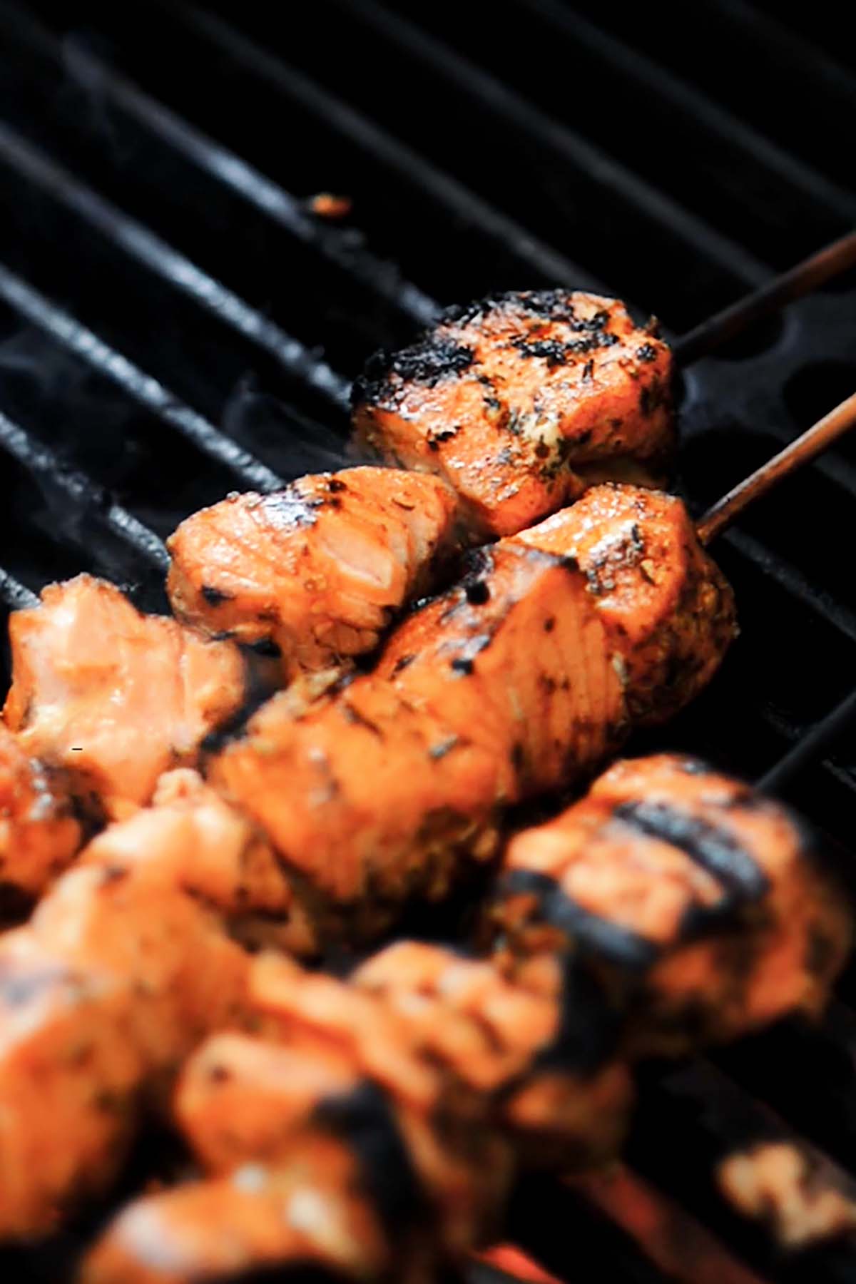 Salmon skewers being grilled over a charcoal fire.