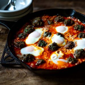Shakshuka with Kofta Meatballs and poached eggs in a cast Iron Skillet.