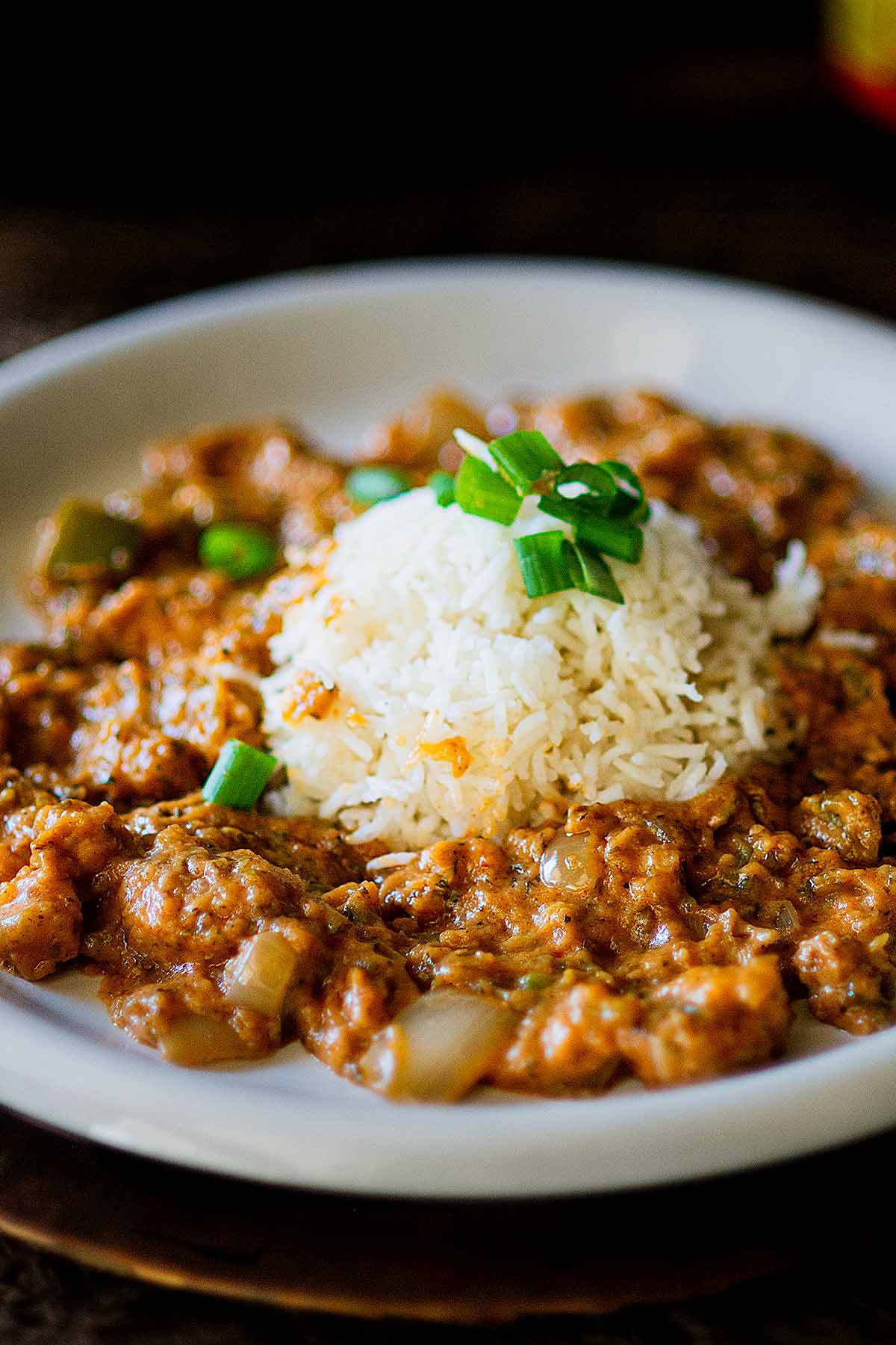 Blackened Alligator Étouffée served on a white plate with white rice.