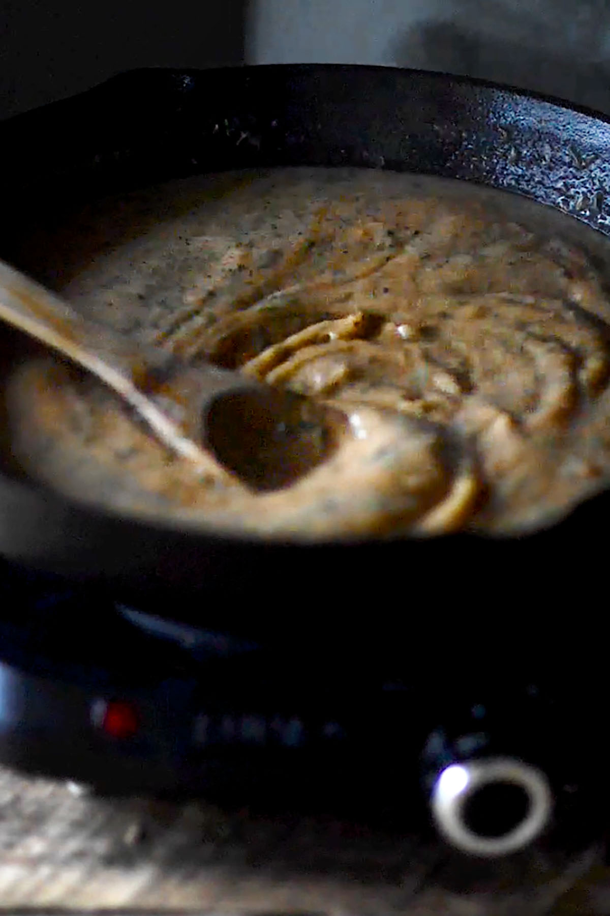 Étouffée roux being simmered and stirred in a cast iron skillet.