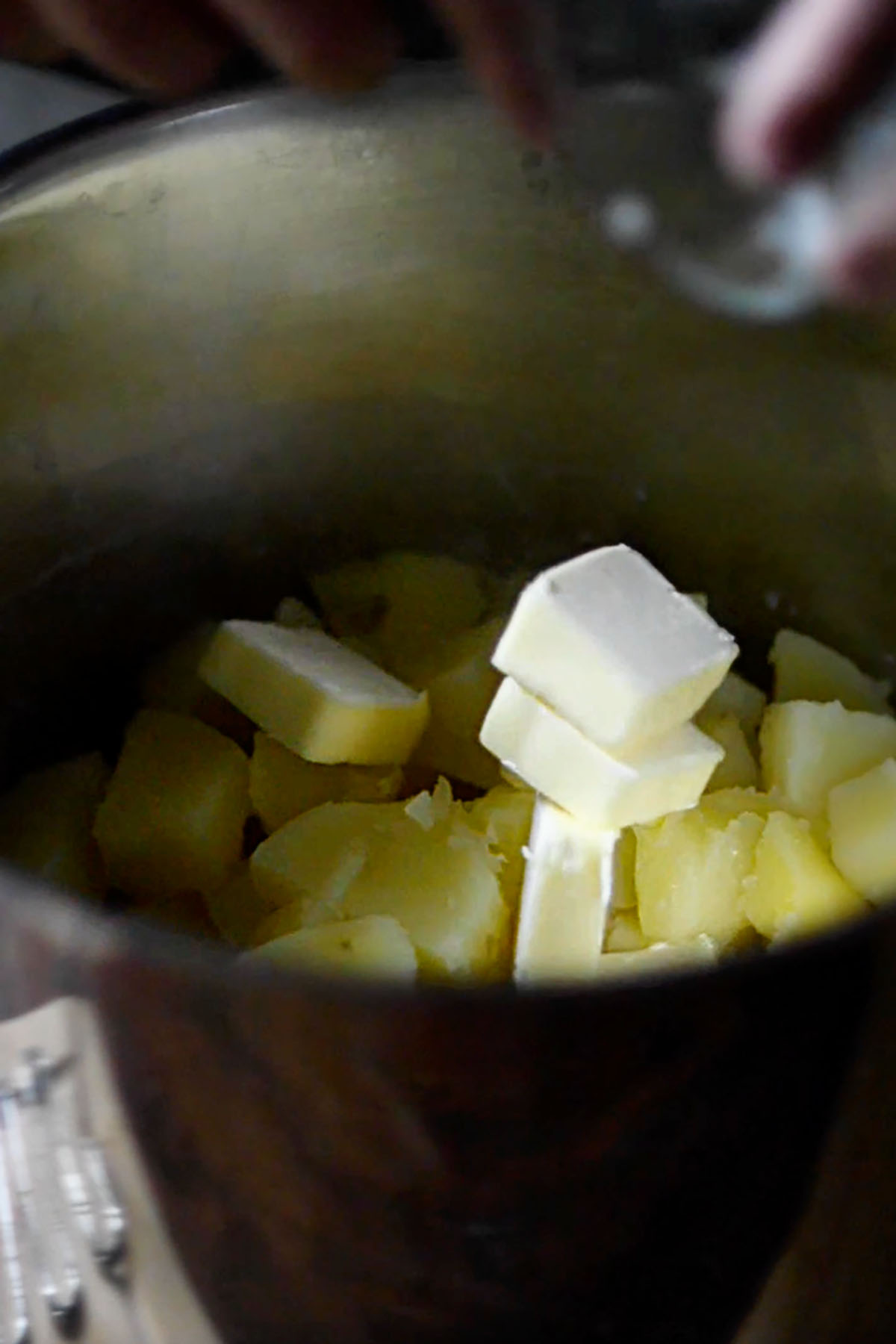 Butter added to a large pot of boiled potatoes.