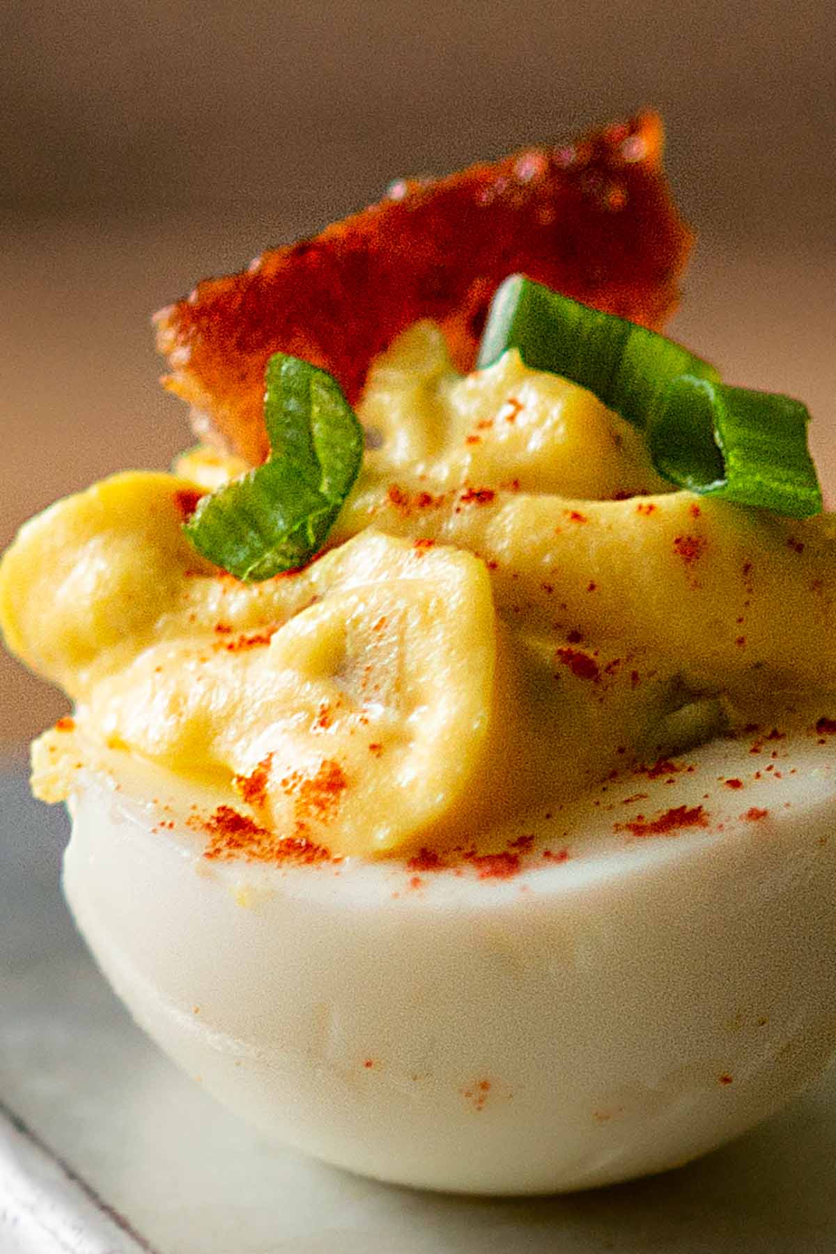Deviled egg topped with a piece of Jalapeño Bacon and sliced green onions.