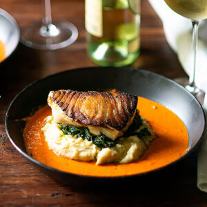 Chilean Sea Bass served with mashed potatoes, spinach, and creamy roasted red pepper sauce.