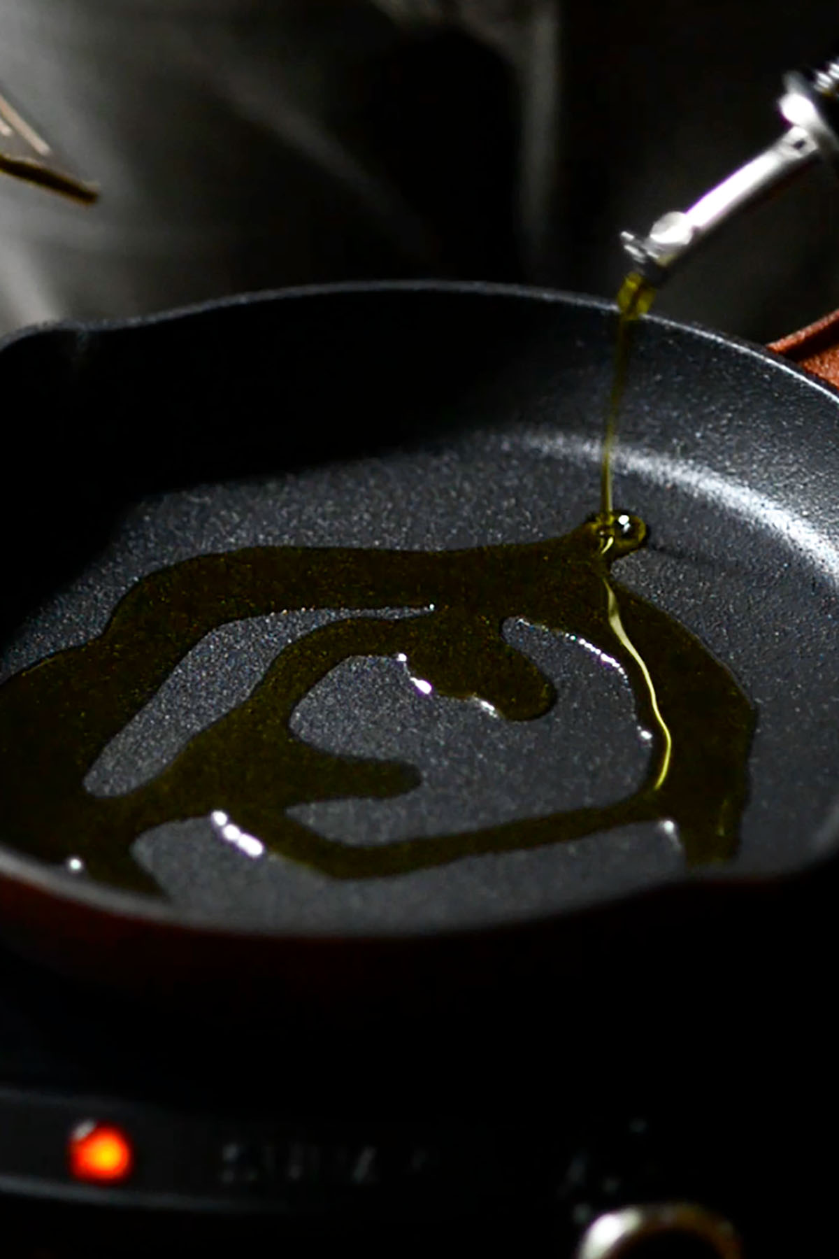Olive oil in a cast iron skillet over a heating element.