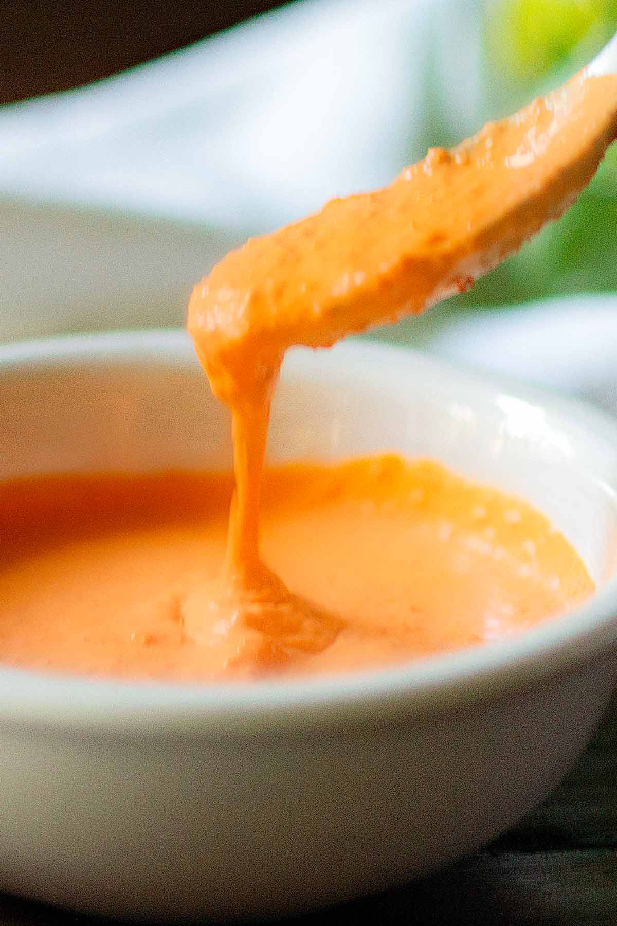 A bowl of roasted red pepper sauce being spooned out.