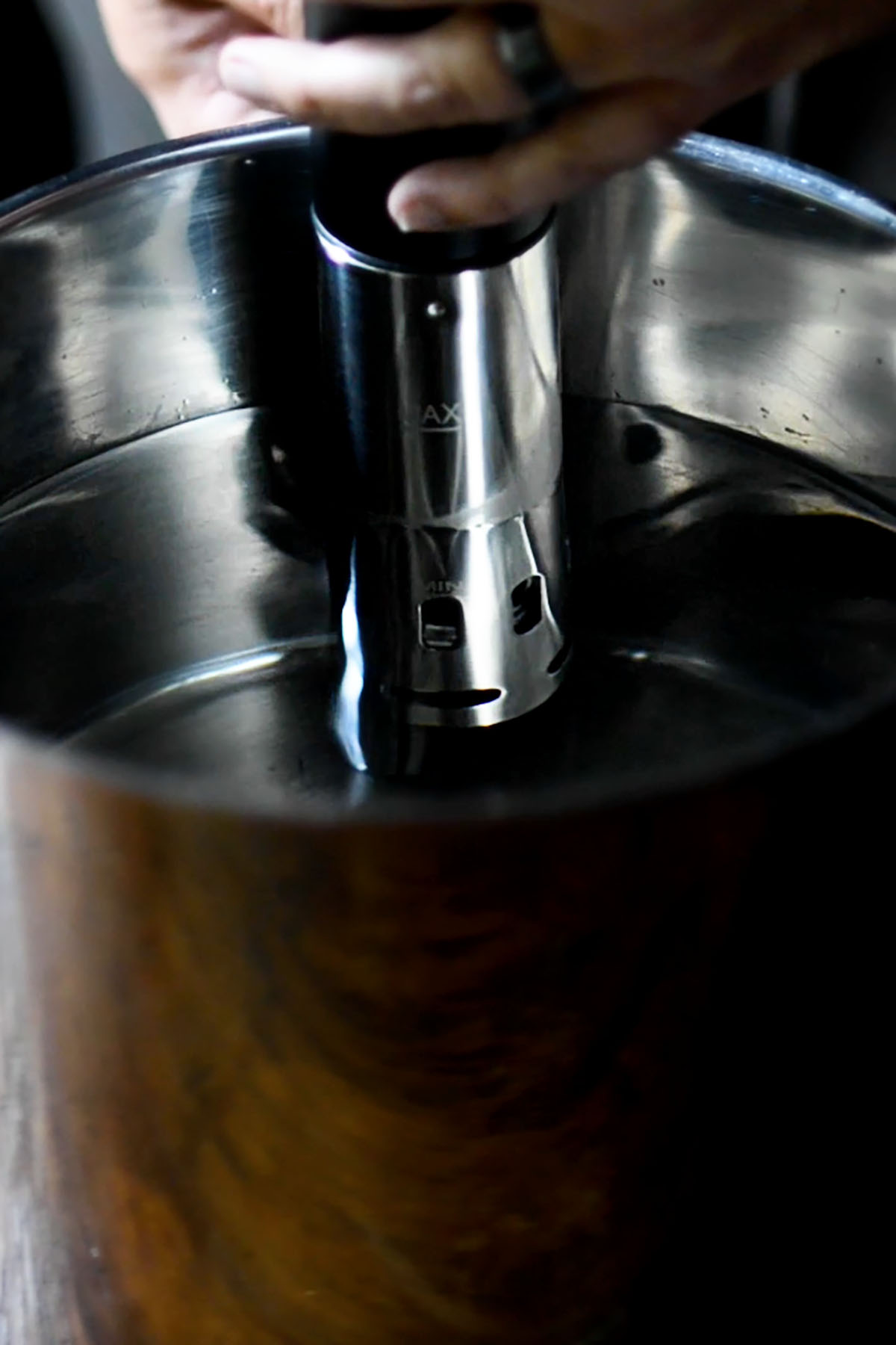 A sous vide circulator being attached to a pot of water.