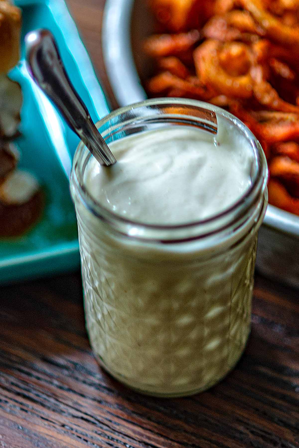 Homemade Arby's Horsey Sauce in a small jar with a spoon and curly fries on the side.