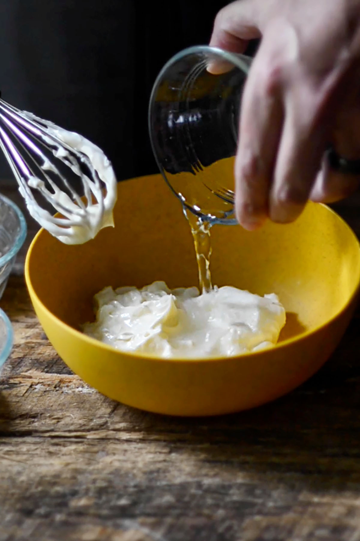 Vinegar being poured into a mixing bowl with mayonnaise.