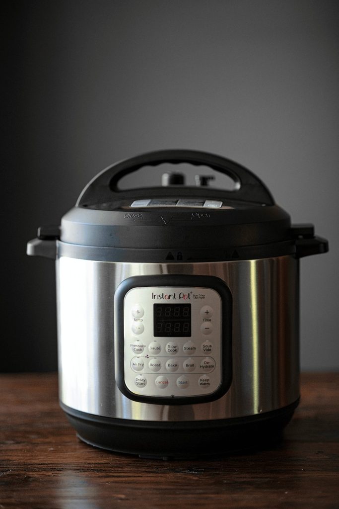 Instant Pot Duo Crisp with Pressure Cooker lid attached sitting on a wooden counter top. 