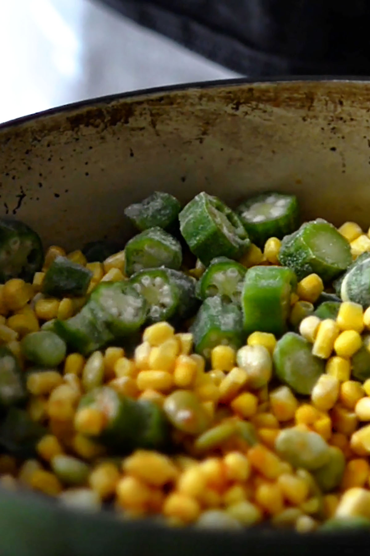 Frozen vegetables added to a a cast iron dutch oven. 