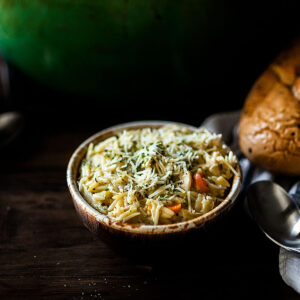 Two bowls of chicken orzo soup served with an Italian bread loaf.