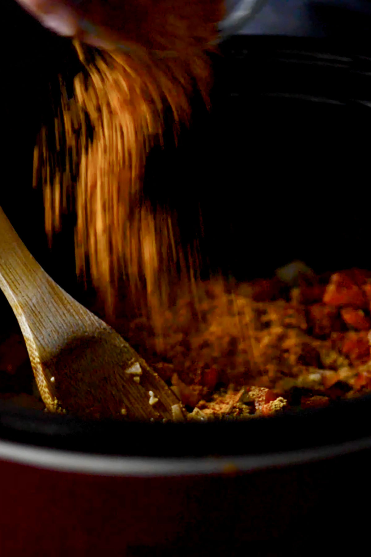 Seasonings and spices being added to a soup in the crock pot.