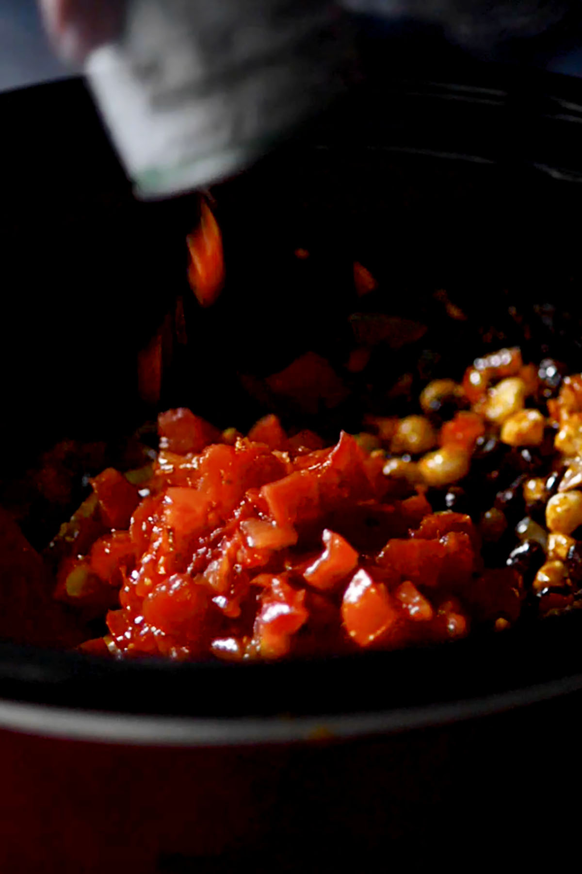 Tomatoes being poured into a slow cooker.