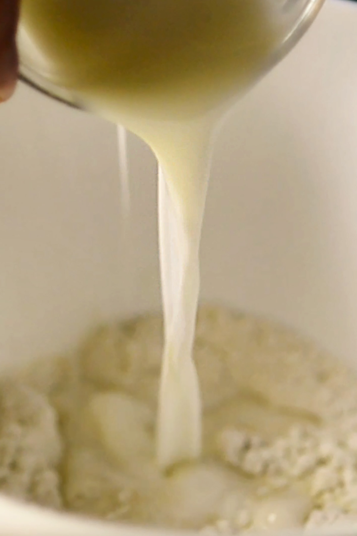 Milk being poured into a mixing bowl of flour.