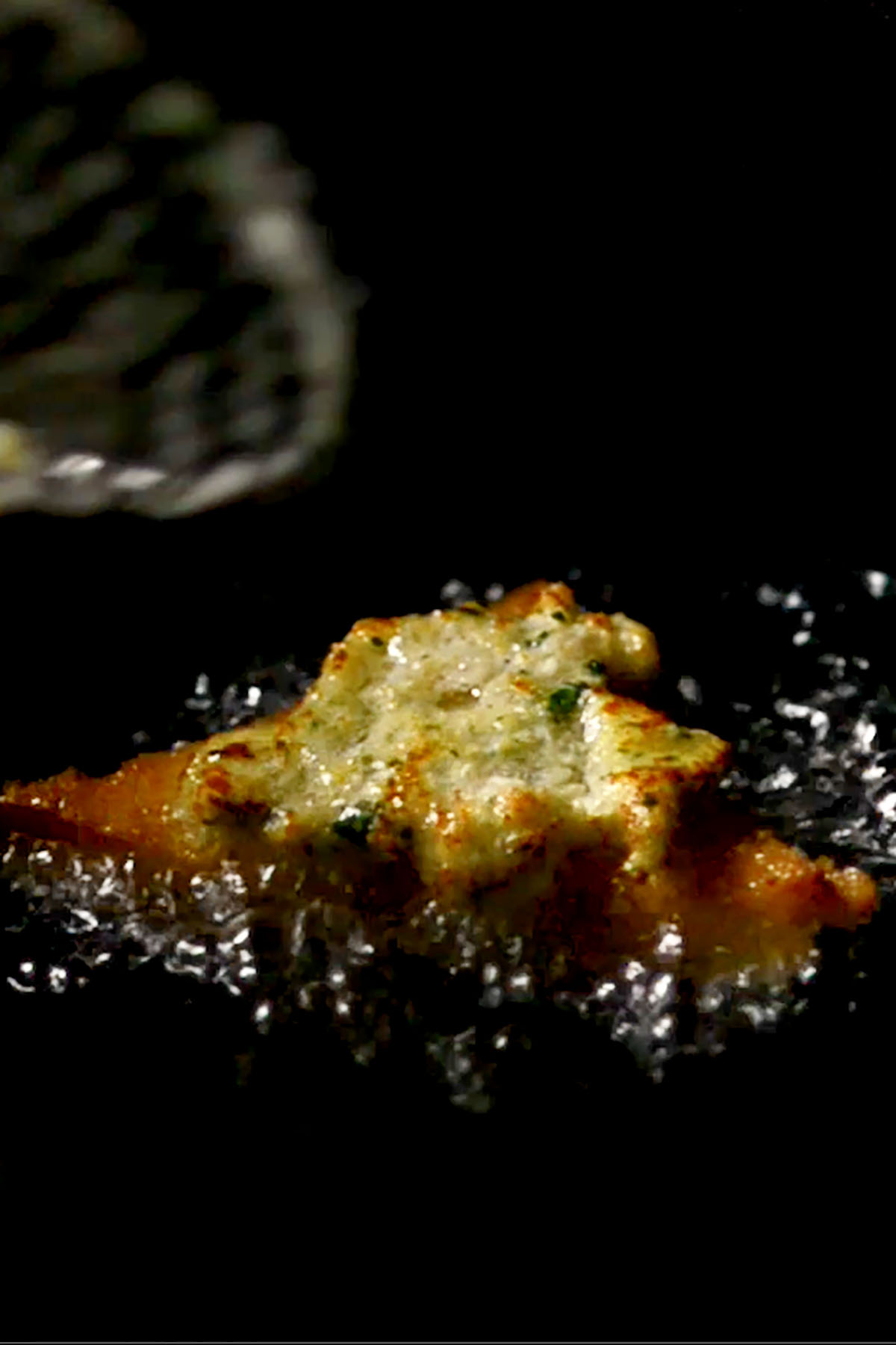 A piece of shrimp toast frying in oil.