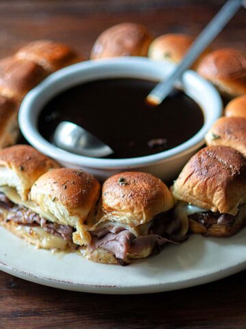 French Dip Sliders plated and served with a bowl of jus.