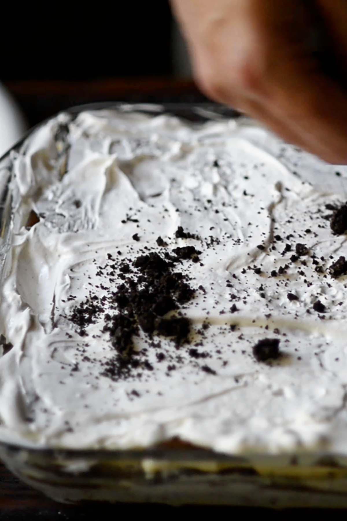 Whipped topping spread over the top of layered ice cream sandwiches with crushed Oreos sprinkled over the top.