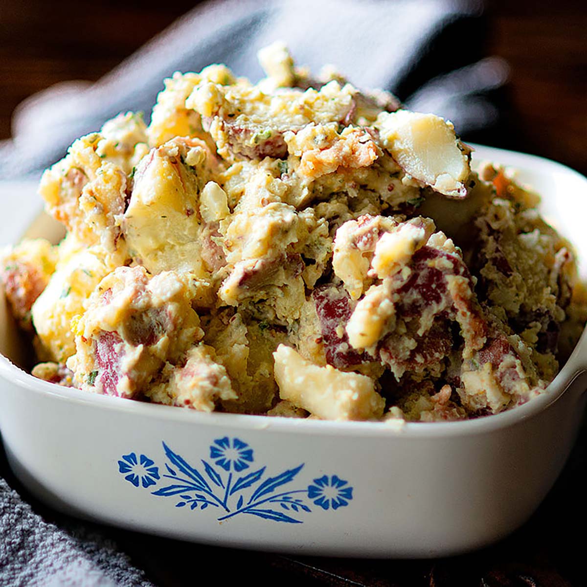A vintage baking dish full of creamy red skin potato salad.