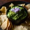Guacamole served with tortilla chips and topped with red onions.